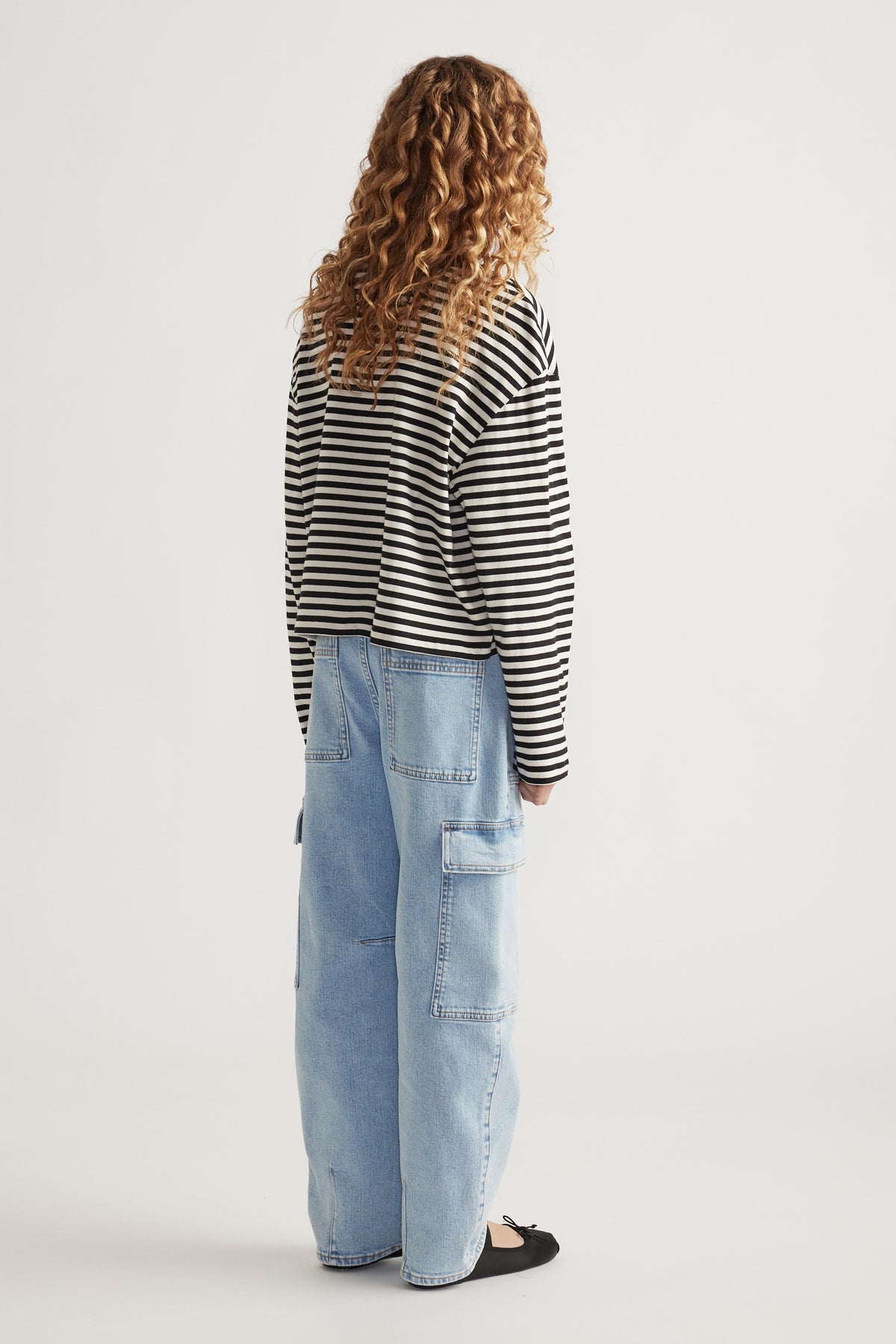 Girl wearing a relaxed fit black and white striped long sleeve tee paired with light blue wide-leg denim pants