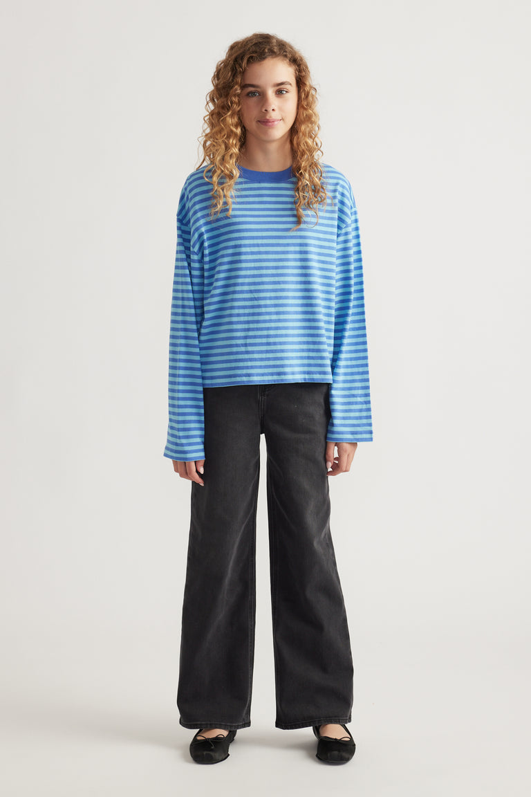 Girl wearing a relaxed blue striped long sleeve tee paired with wide-leg black jeans and black ballet flats