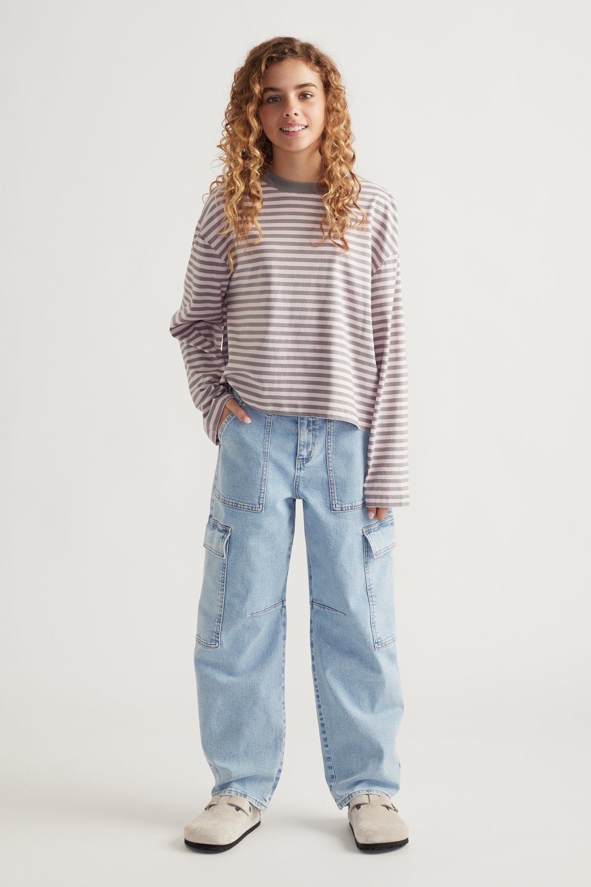 Girl wearing a relaxed fit striped long sleeve top paired with light blue wide-leg cargo jeans and casual shoes