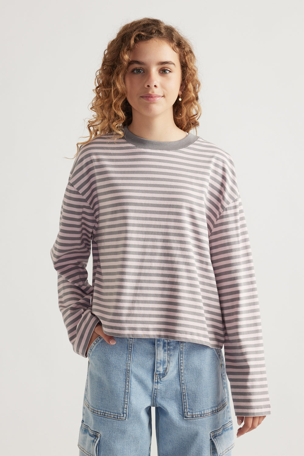 Girl wearing a relaxed-fit striped long sleeve tee paired with light blue cargo denim pants in a casual pose
