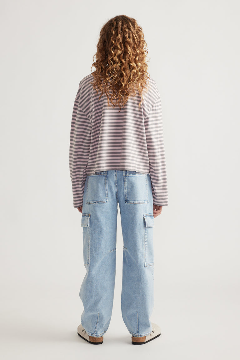 Girl with curly hair wearing a relaxed striped long sleeve top and light wash cargo jeans with wide legs and pockets