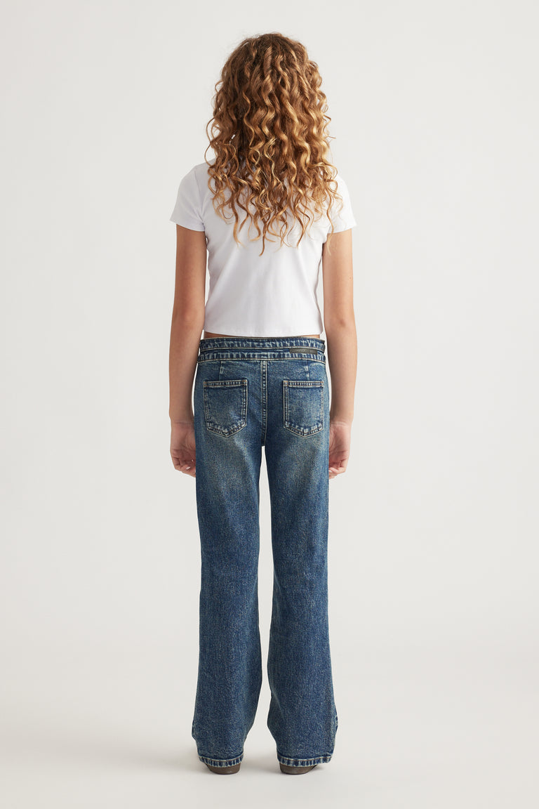 Rear view of teen girl wearing mid-rise bootcut denim jeans paired with a short-sleeve white top