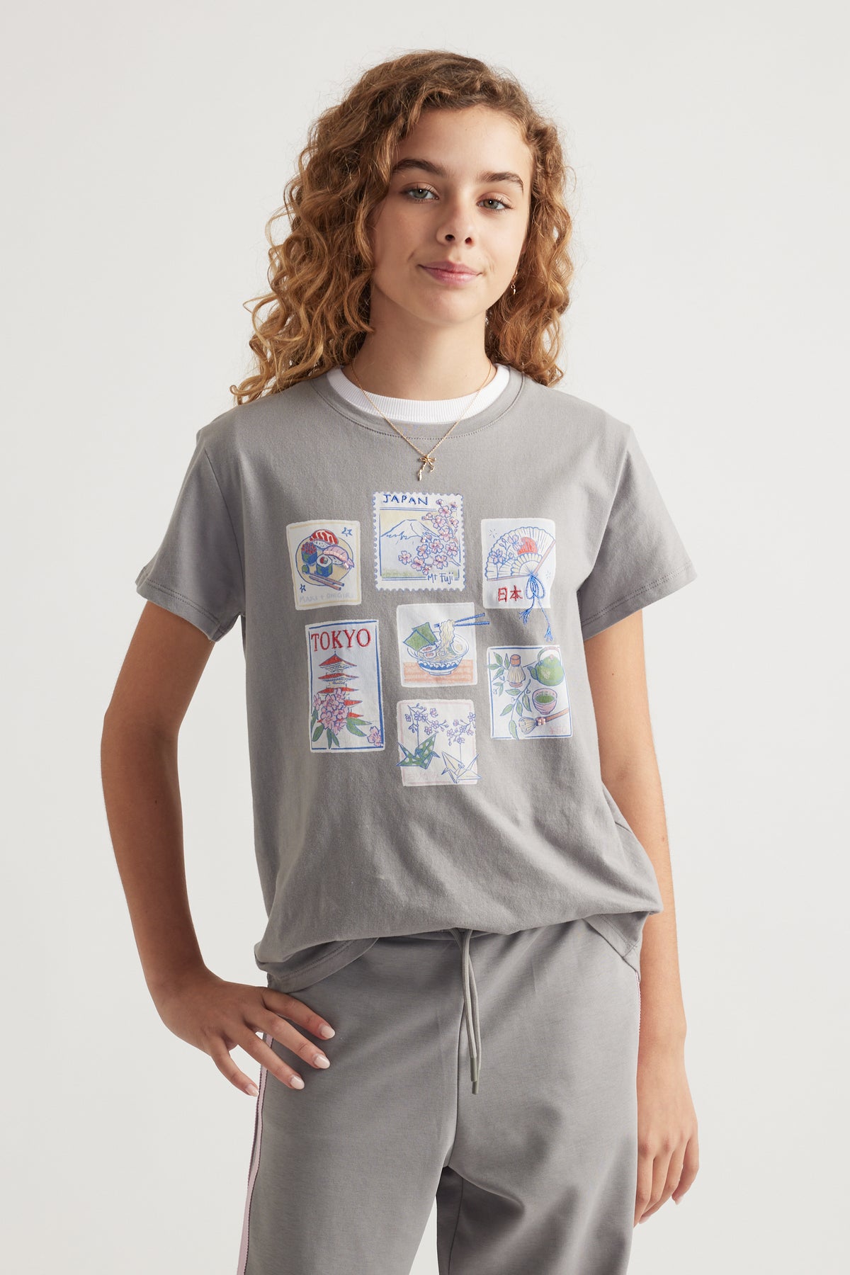 Girl wearing a relaxed grey tee with Tokyo-themed graphic prints paired with coordinating grey drawstring pants