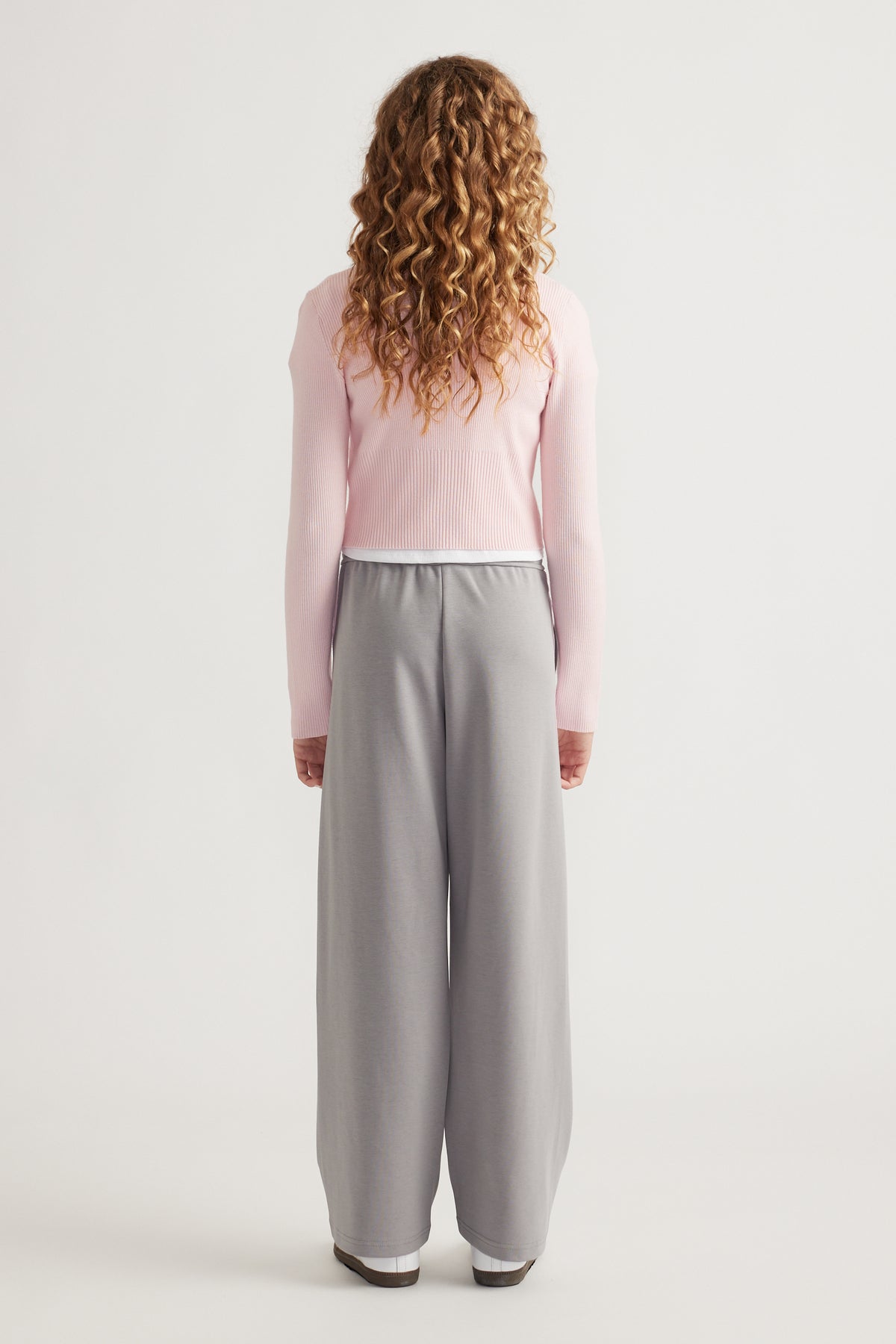 Teen girl wearing soft grey wide-leg pants with elasticated waist paired with a fitted light pink long-sleeve top