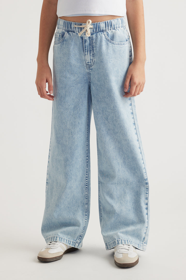 Girl wearing light blue jeans with an elastic drawstring waist and sneakers