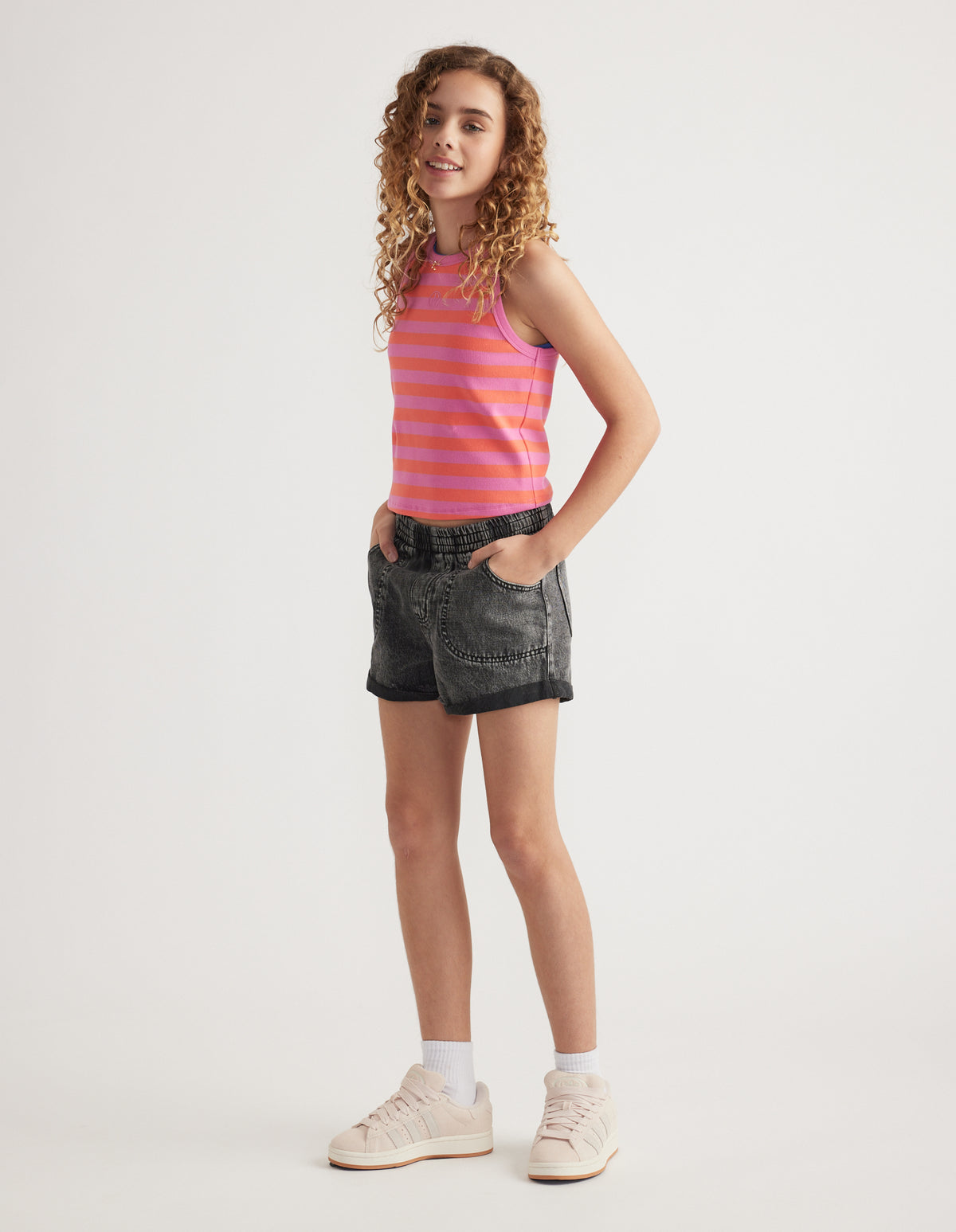 Girl wearing black denim pull-on shorts with cuffed hems, a striped tank top and sneakers