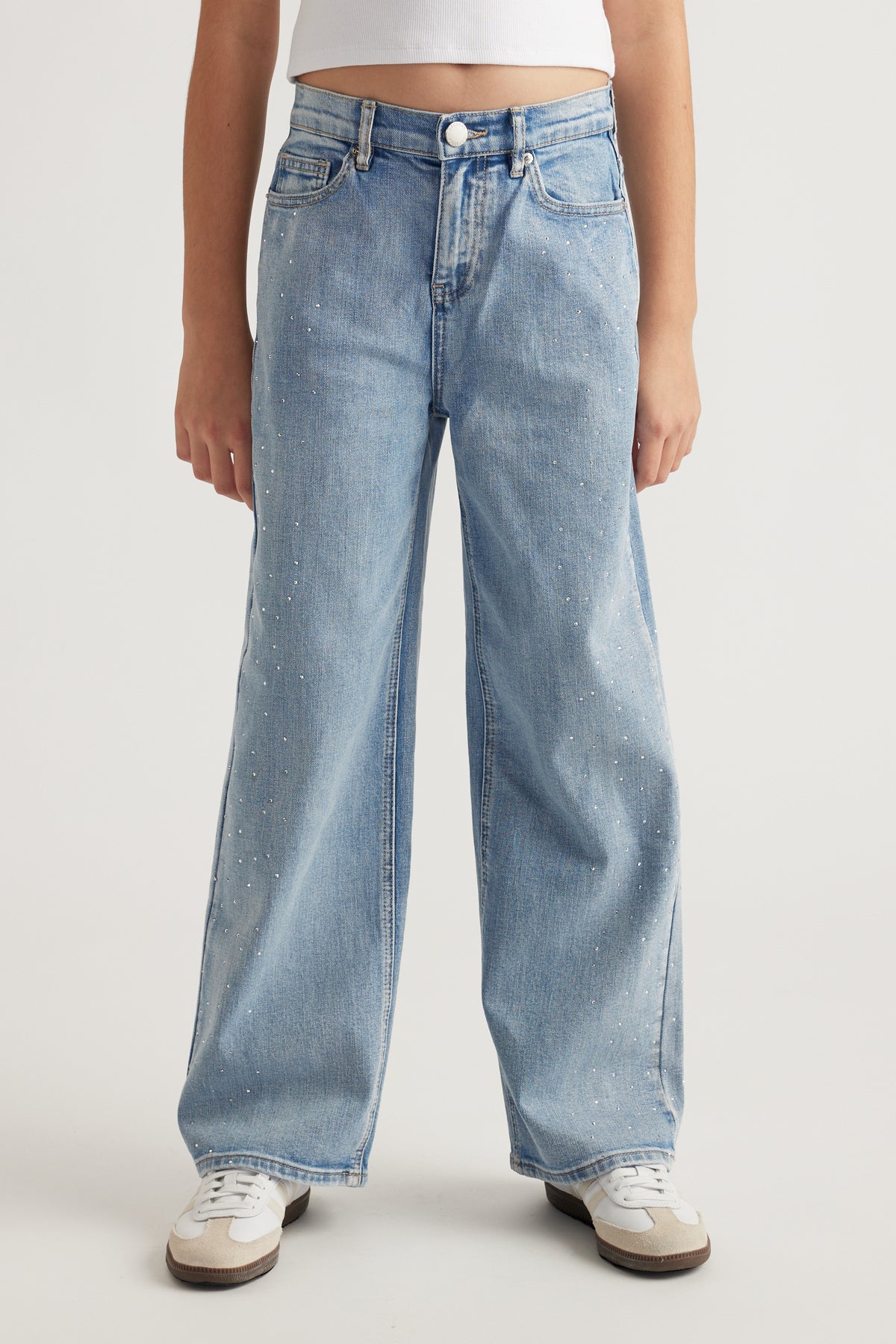 Front view of teen girl wearing light wash mid-rise jeans with crystal embellishments and relaxed straight leg fit