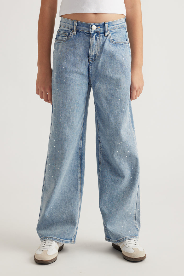 Front view of teen girl wearing light wash mid-rise jeans with crystal embellishments and relaxed straight leg fit