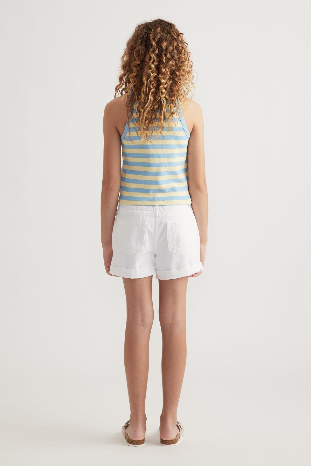 Girl wearing a blue and yellow striped rib racer tank with white shorts, viewed from behind