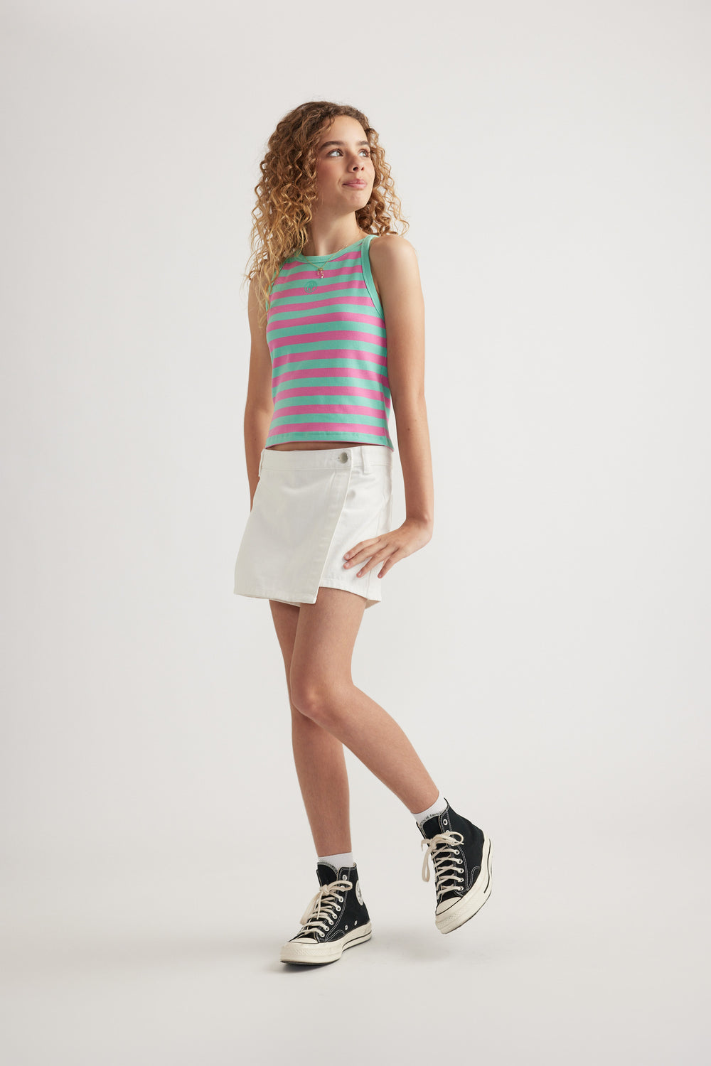 Girl wearing a pink and green striped rib racer tank with white shorts and sneakers