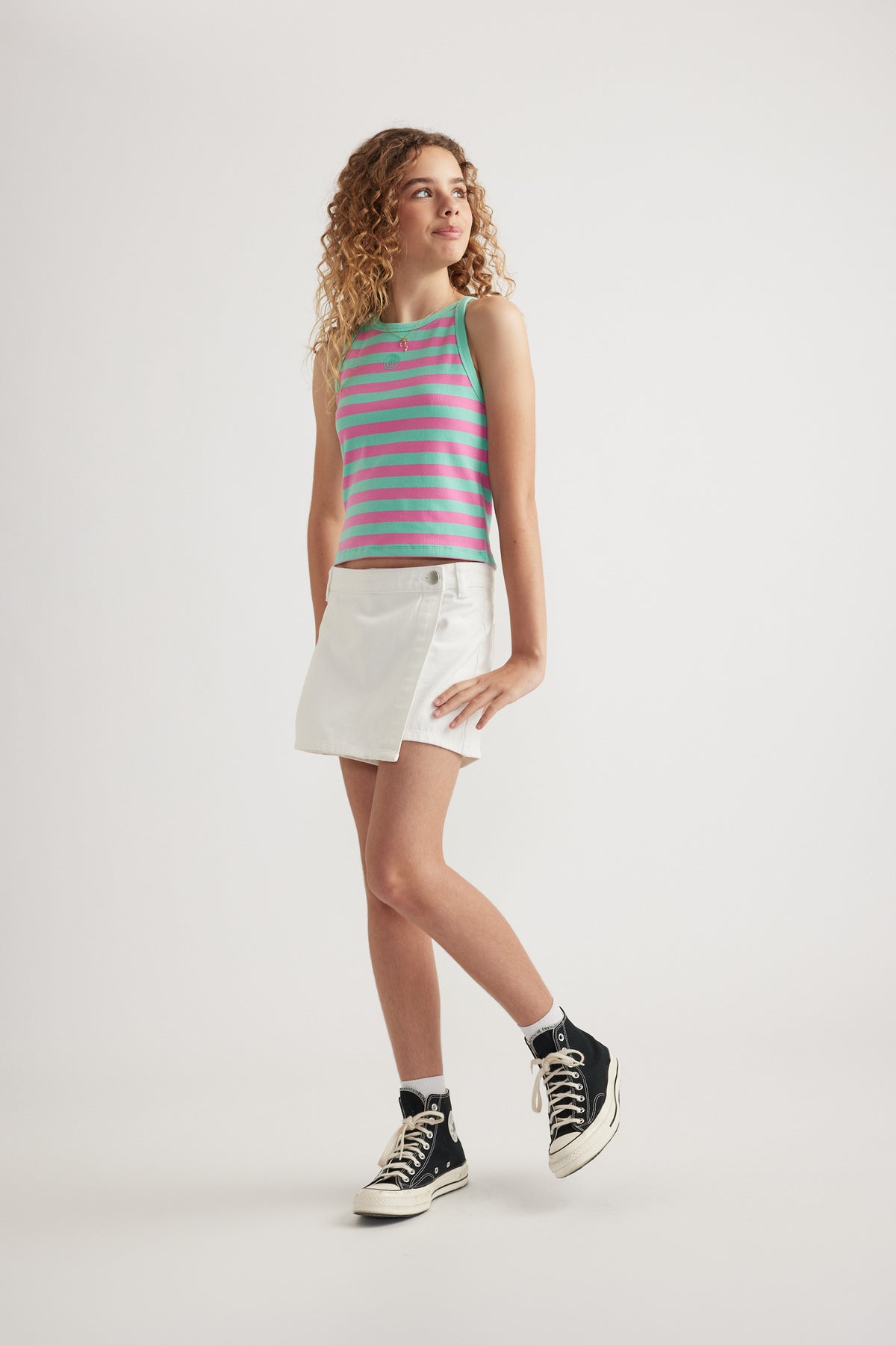 Girl wearing a pink and green striped rib racer tank with white shorts and sneakers