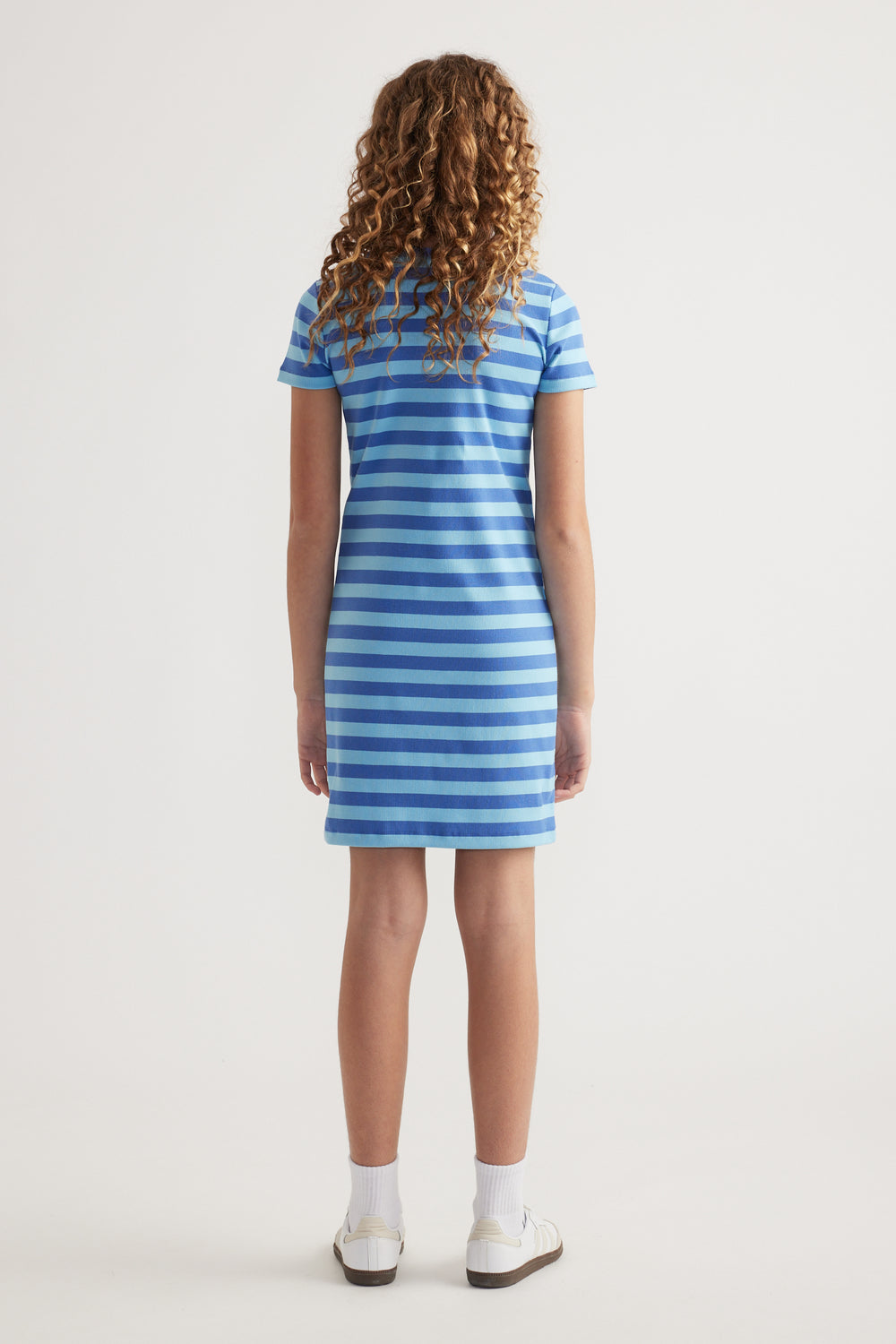 Back view of girl wearing a blue and white striped ribbed T-shirt dress with short sleeves and an above-knee hem