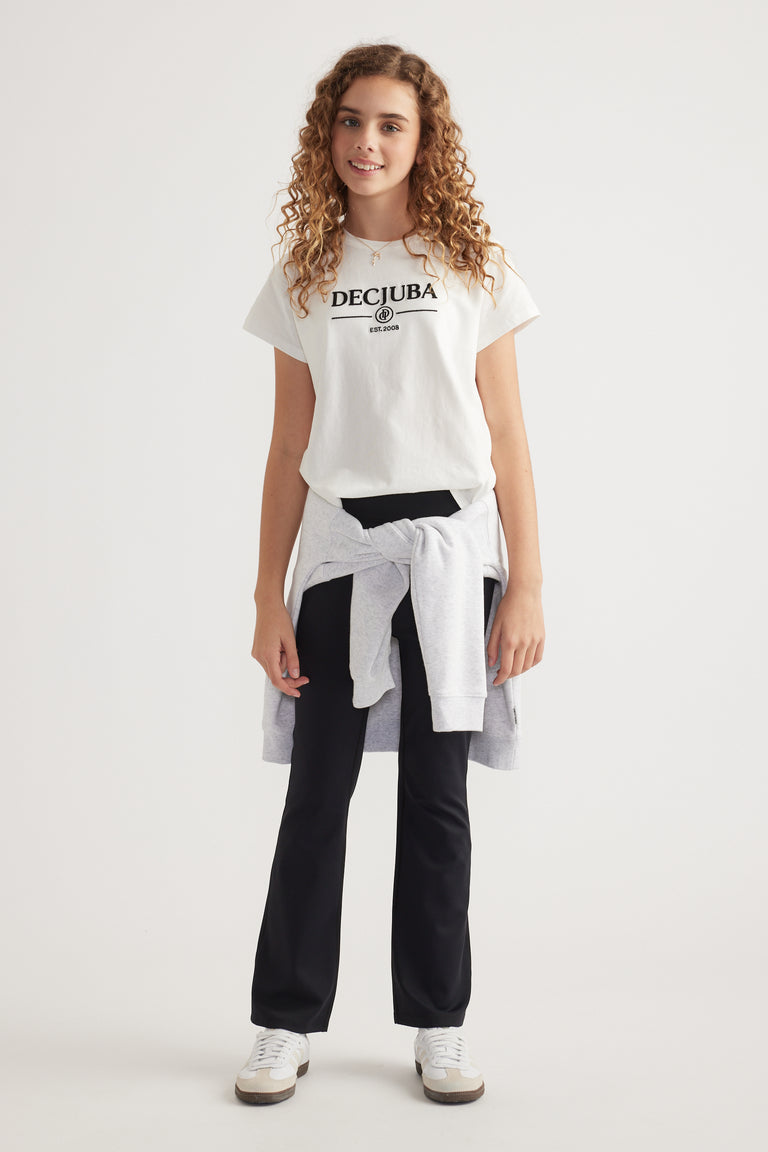 Girl wearing a white heritage graphic tee with black pants, a sweatshirt tied at the waist and sneakers