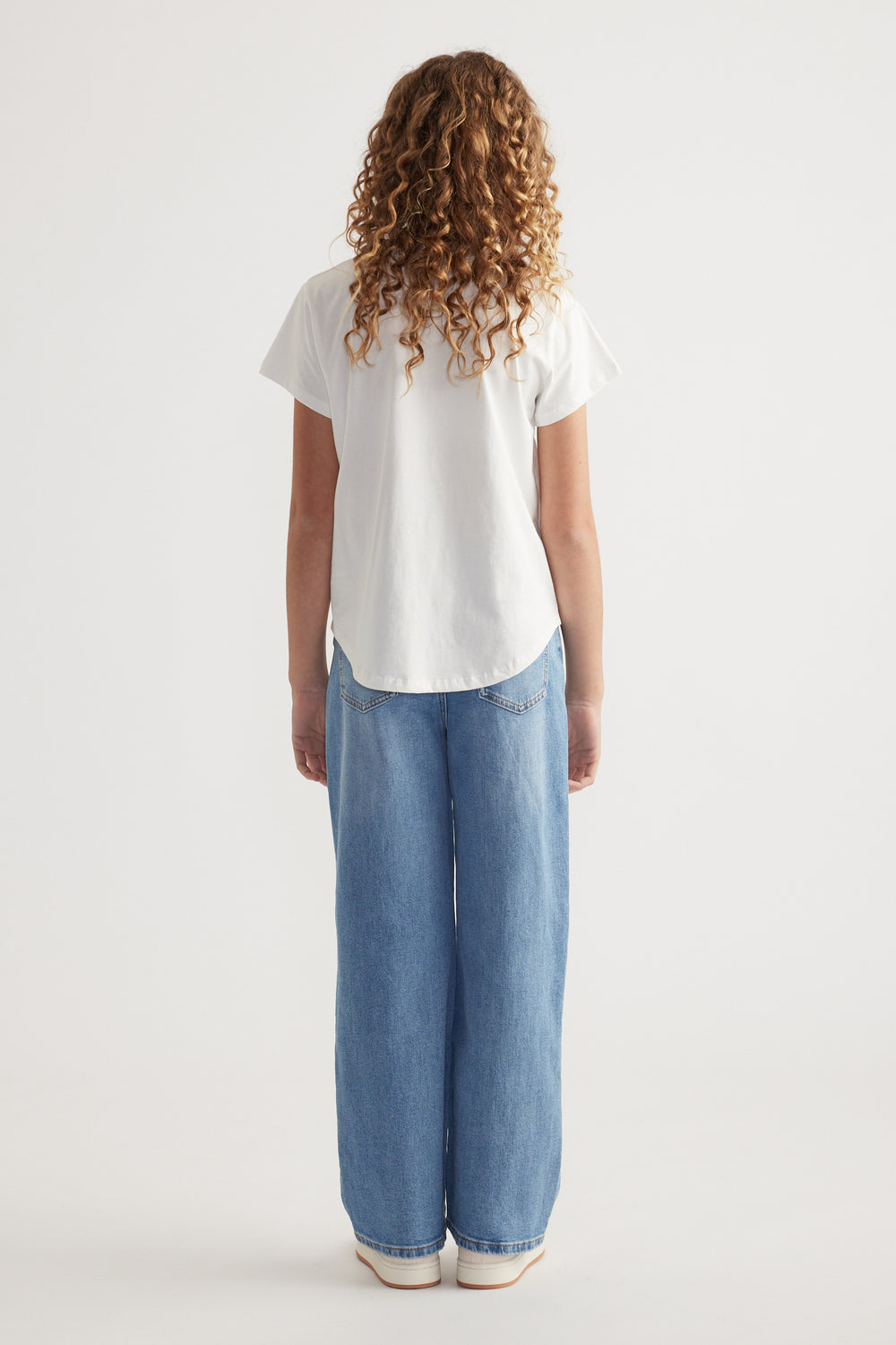 Back view of girl in a white crew neck T-shirt and relaxed blue wide-leg jeans
