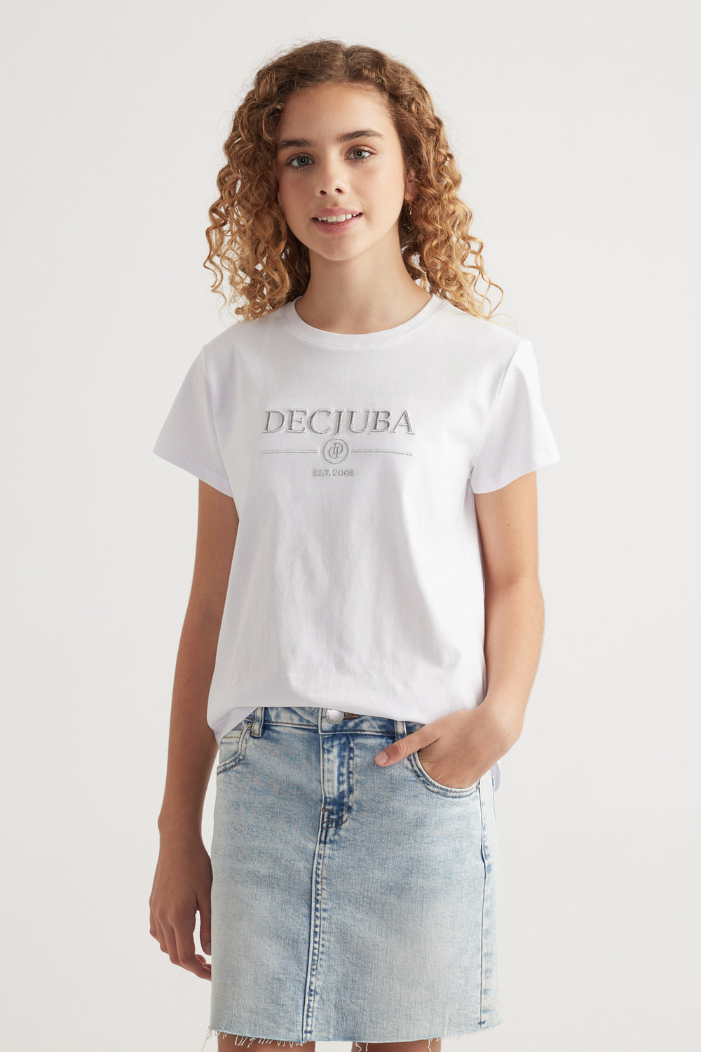 Girl wearing a white Decjuba heritage graphic T shirt with a light wash denim skirt