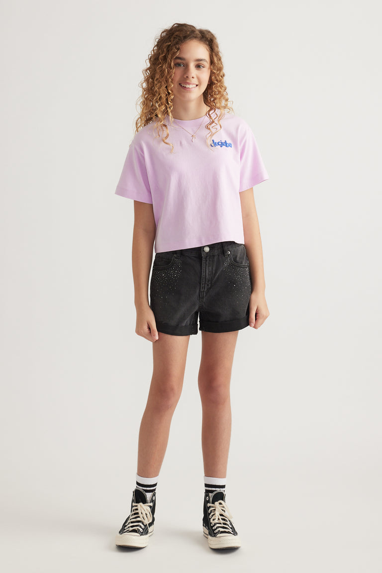 Girl wearing a pink graphic tee with black rhinestone denim shorts and high top sneakers