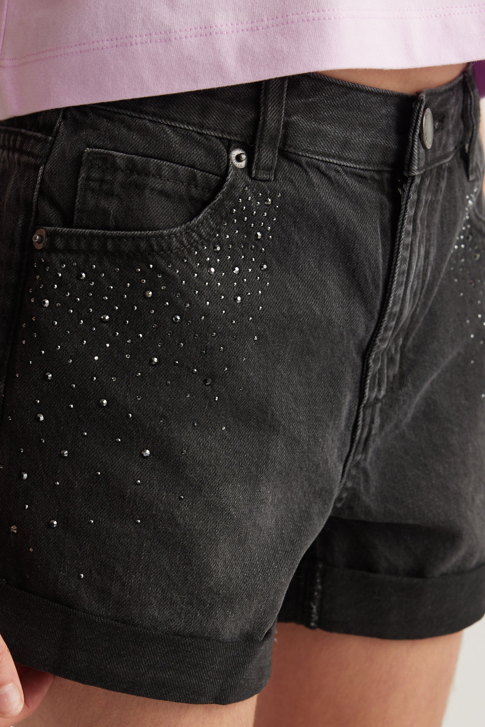 Close up of black denim shorts with rhinestone detailing a high rise waist and rolled cuffs