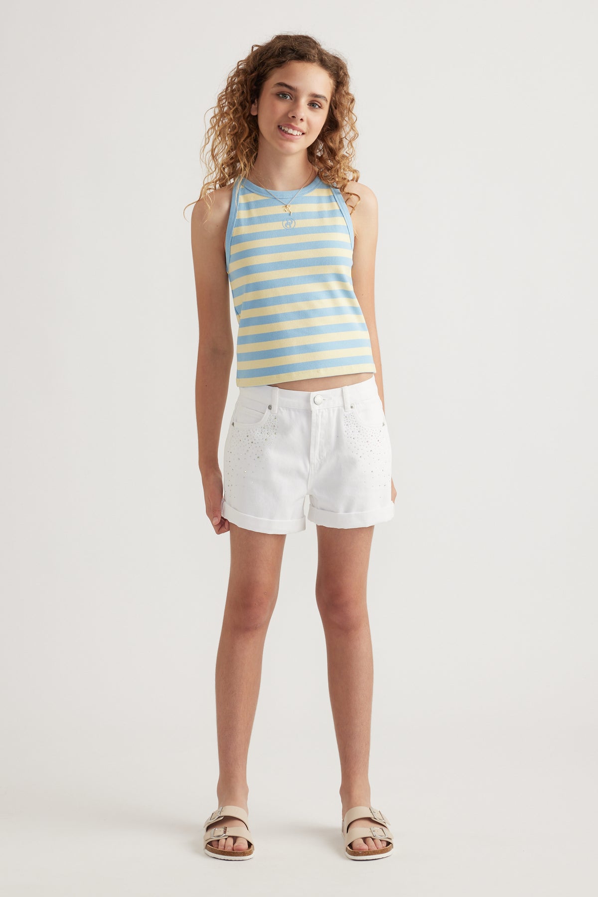 Girl wearing white high rise denim shorts with rolled cuffs and a blue striped tank top
