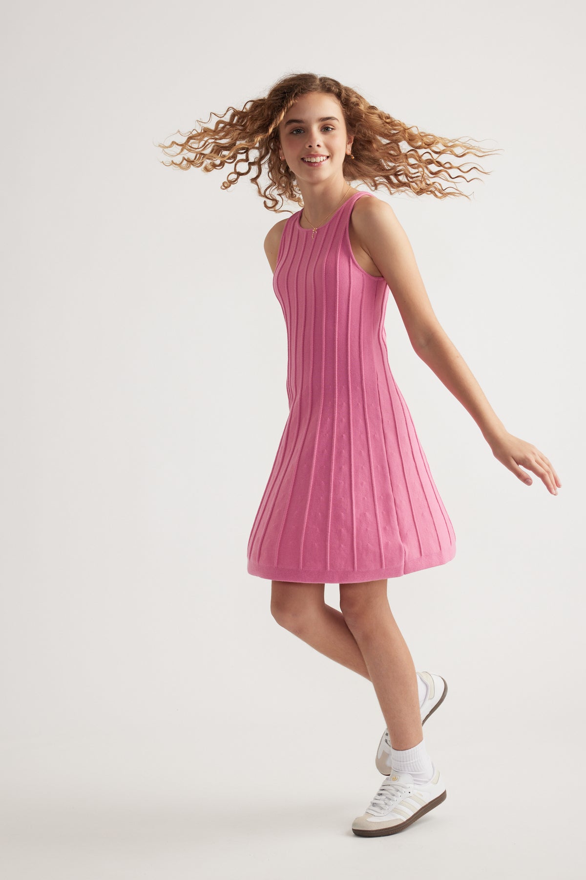 Girl wearing a pink sleeveless knit fit and flare mini dress with white sneakers