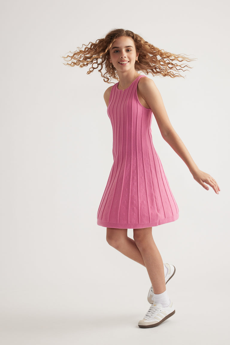 Girl wearing a pink sleeveless knit fit and flare mini dress with white sneakers