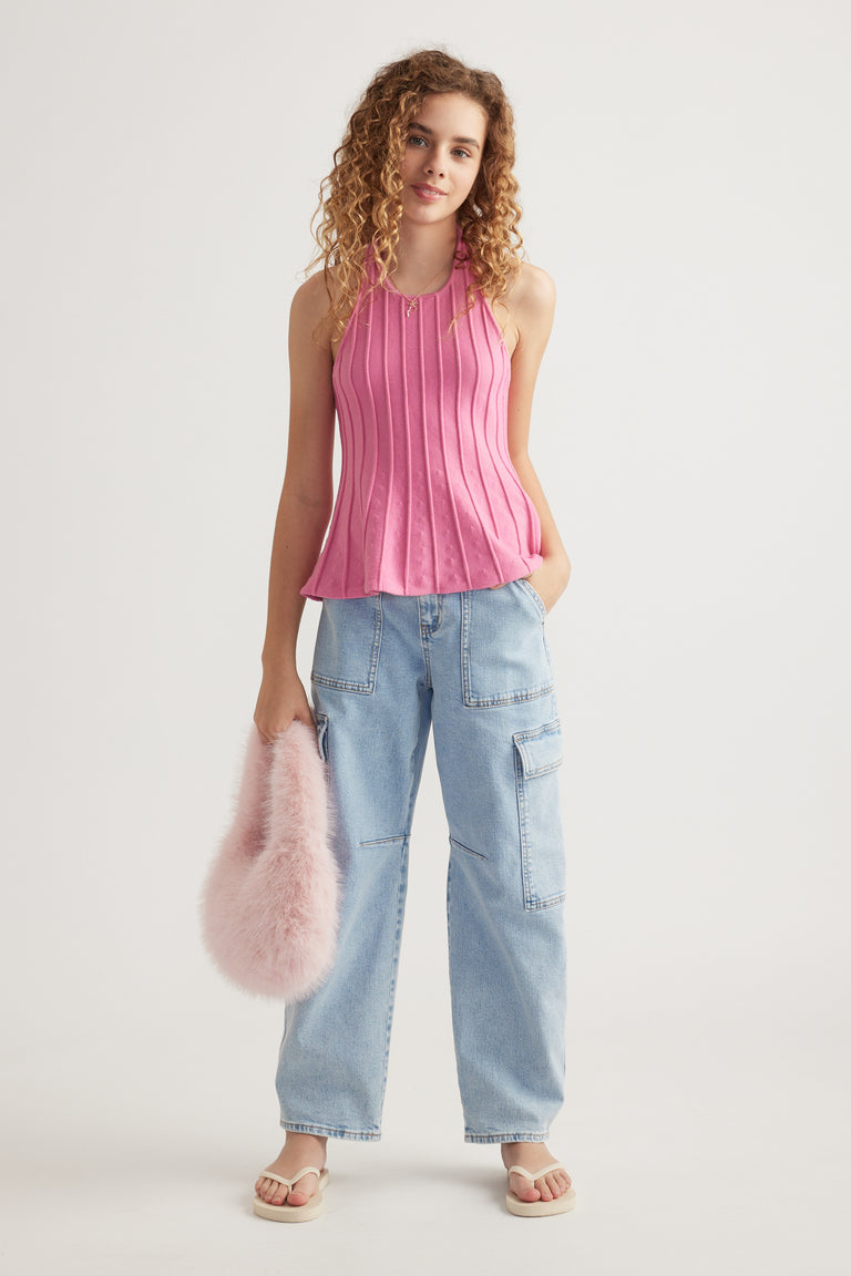 Girl wearing a pink pleated halter top with light blue cargo jeans and a fluffy pink bag