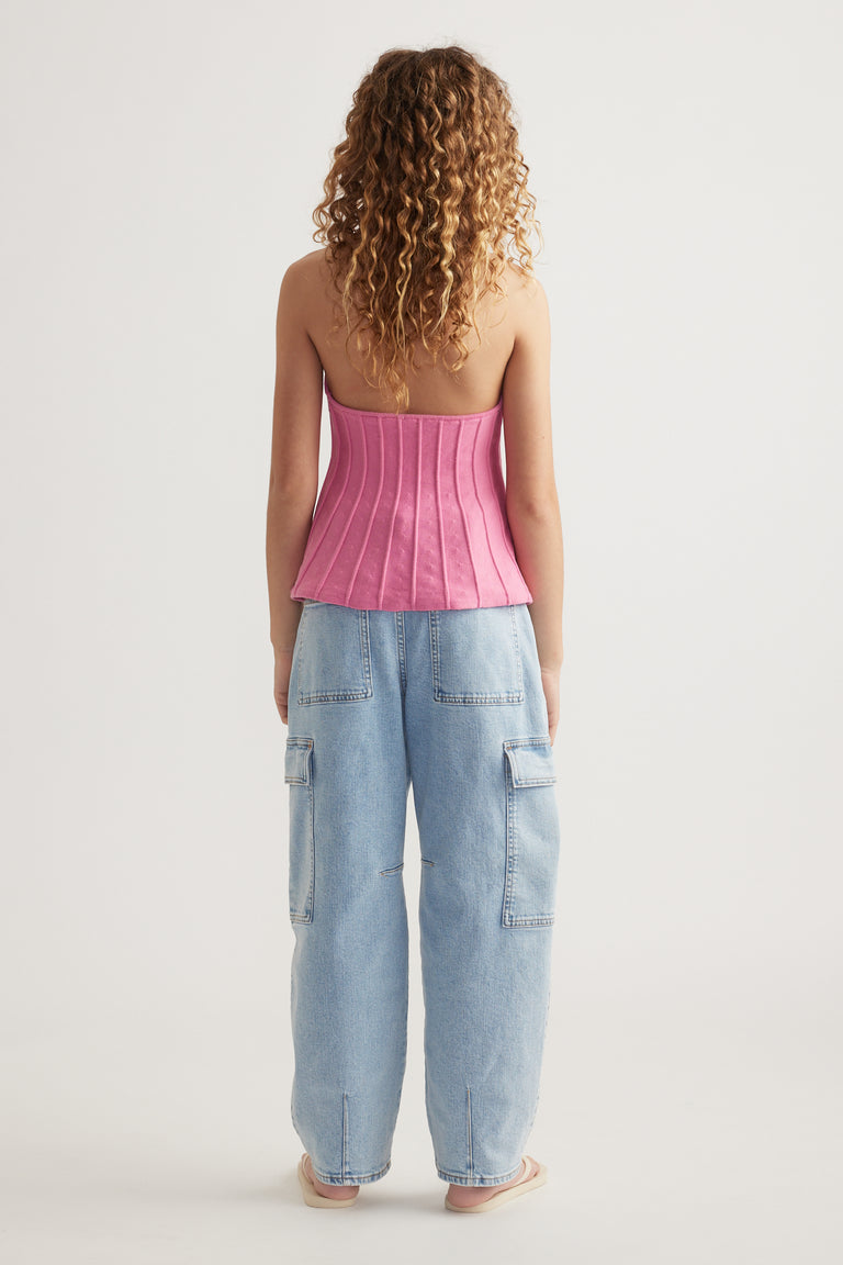 Girl wearing a pink halter neck top with panelled detailing and light blue cargo jeans from the back