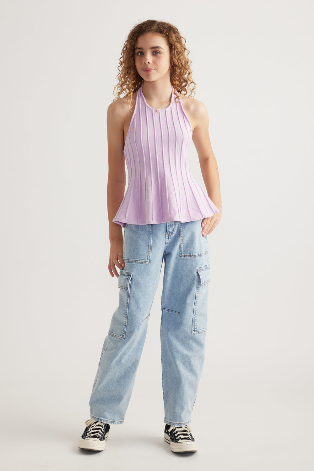 Model wearing a lilac pleated halter top with light blue cargo jeans and black and white sneakers