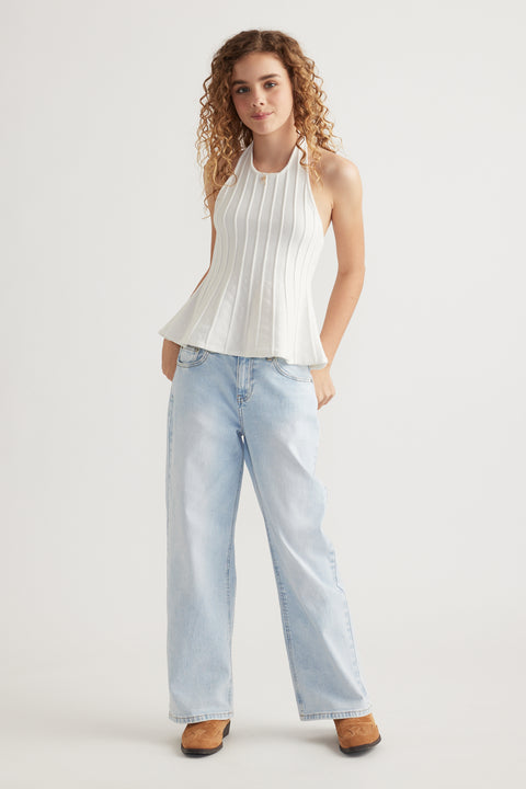 Young woman wearing a white pleated halter top with light blue wide leg jeans and brown shoes