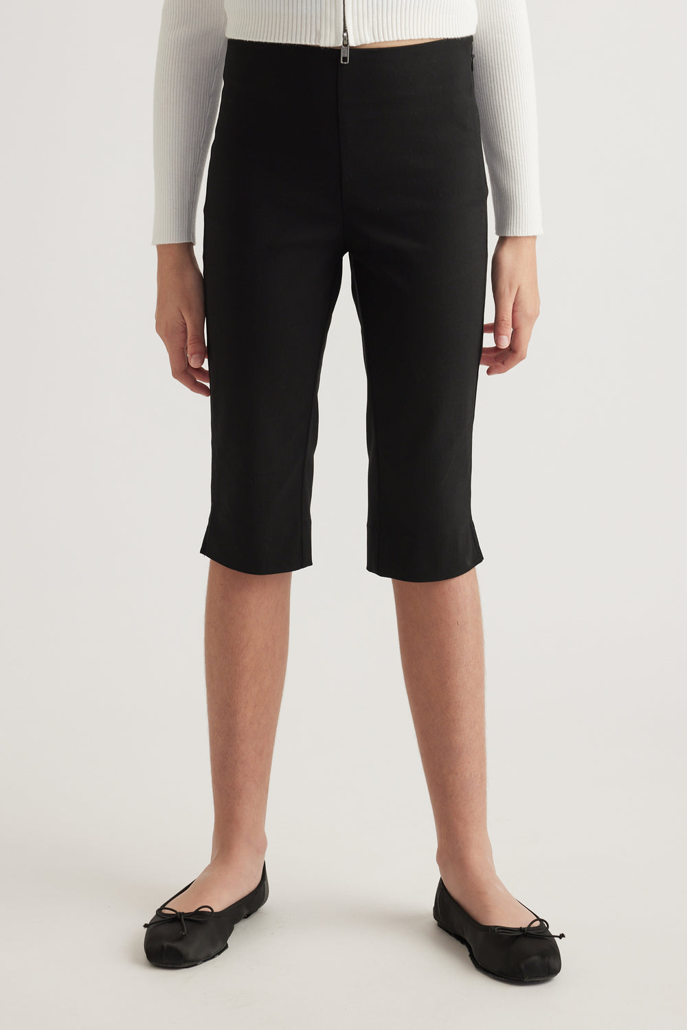 Model wearing black high rise capri pants with a slim leg and below knee length