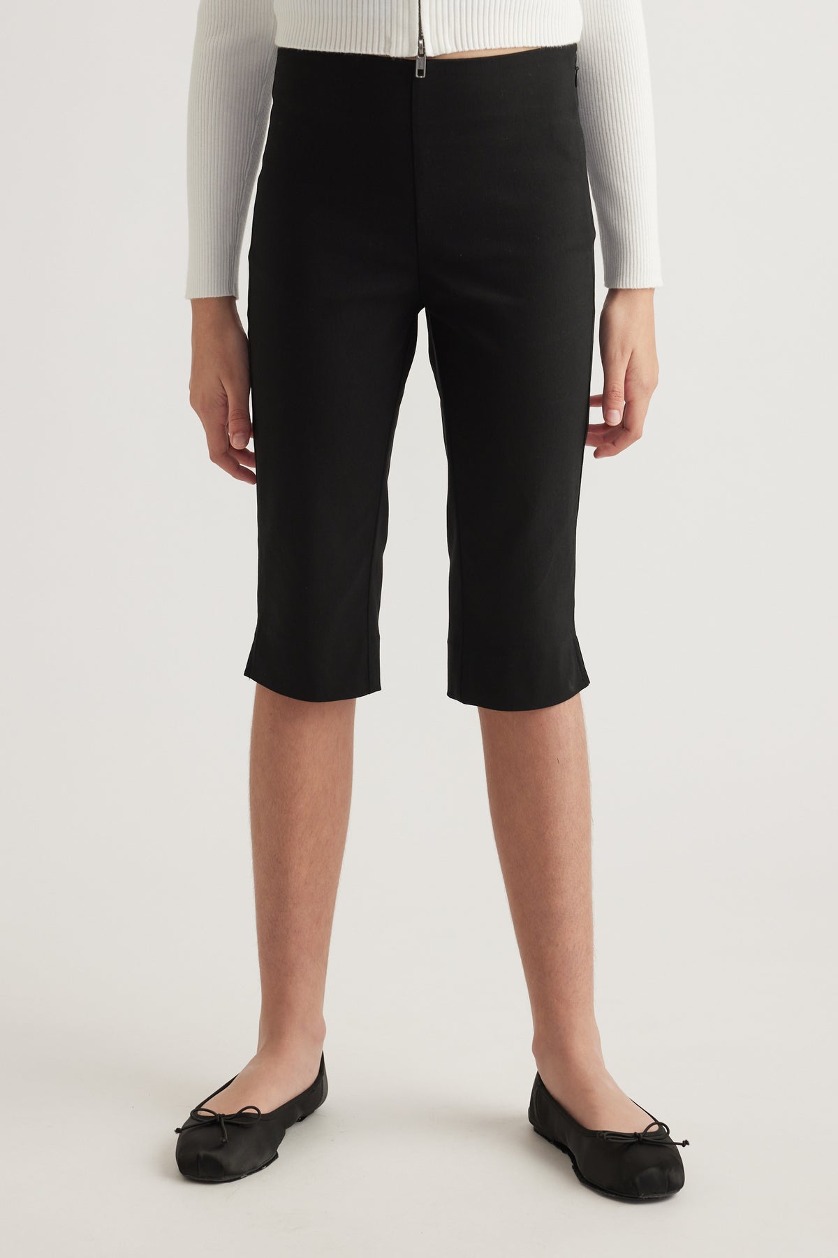 Model wearing black high rise capri pants with a slim leg and below knee length