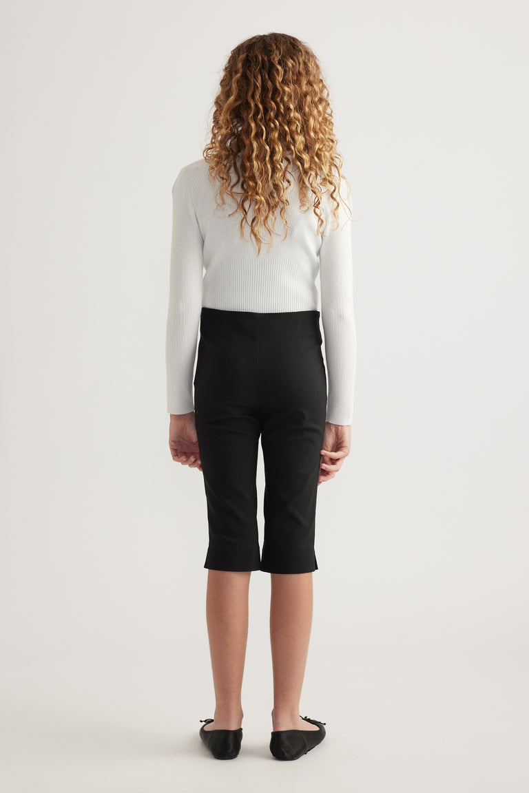 Girl wearing black high rise capri pants with a white ribbed sweater