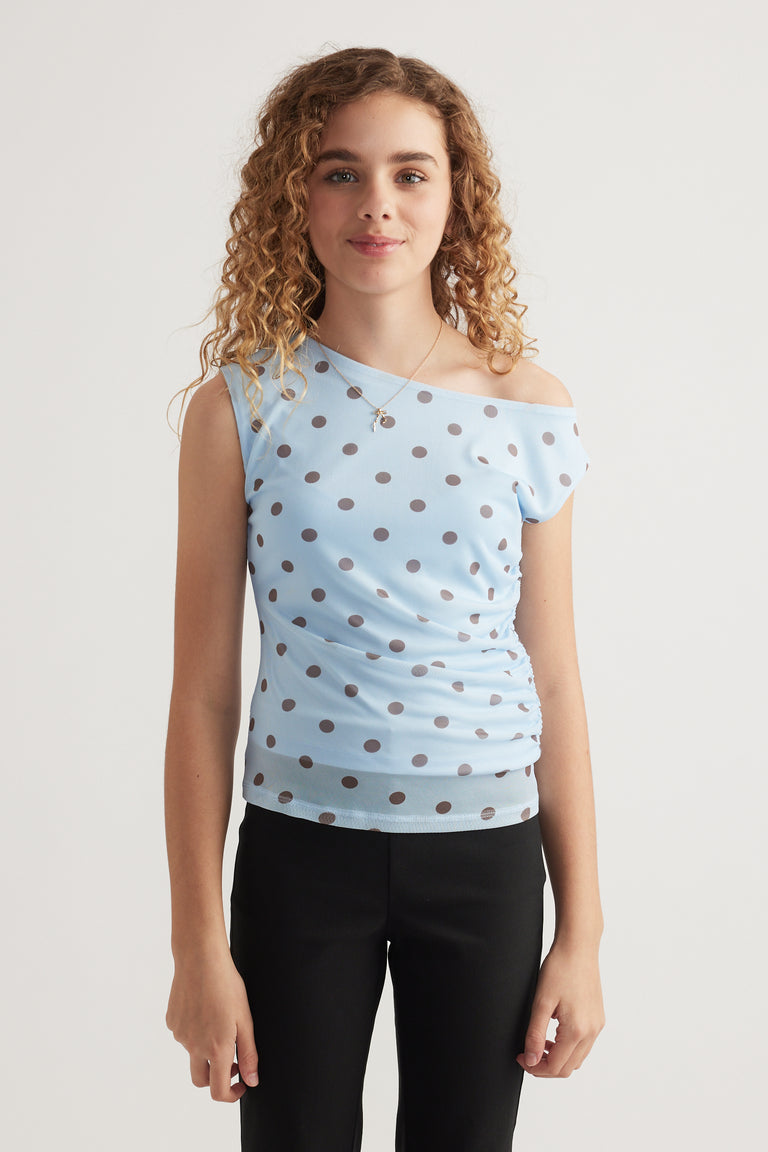 Girl wearing a light blue polka dot asymmetric top with black pants
