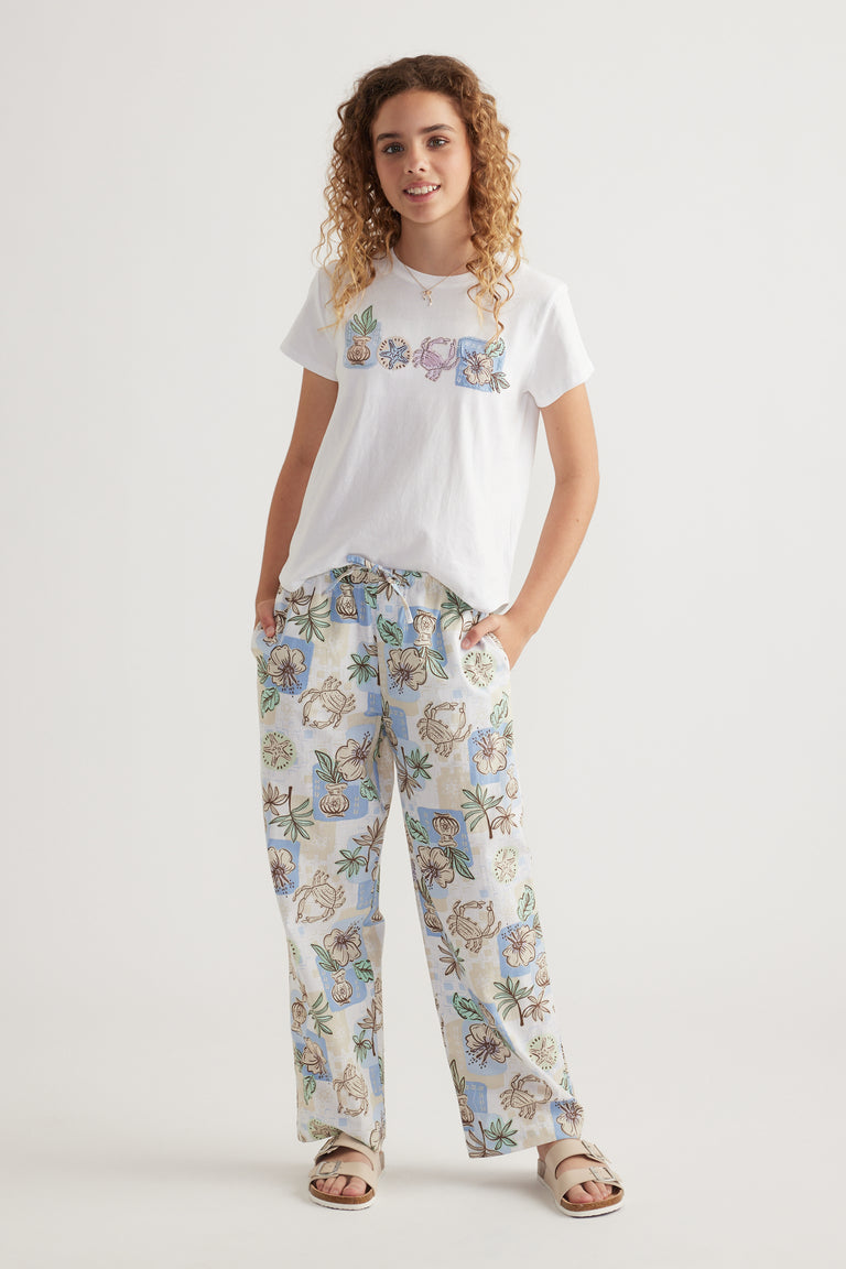 Girl wearing floral wide leg pants with a white graphic tee and sandals