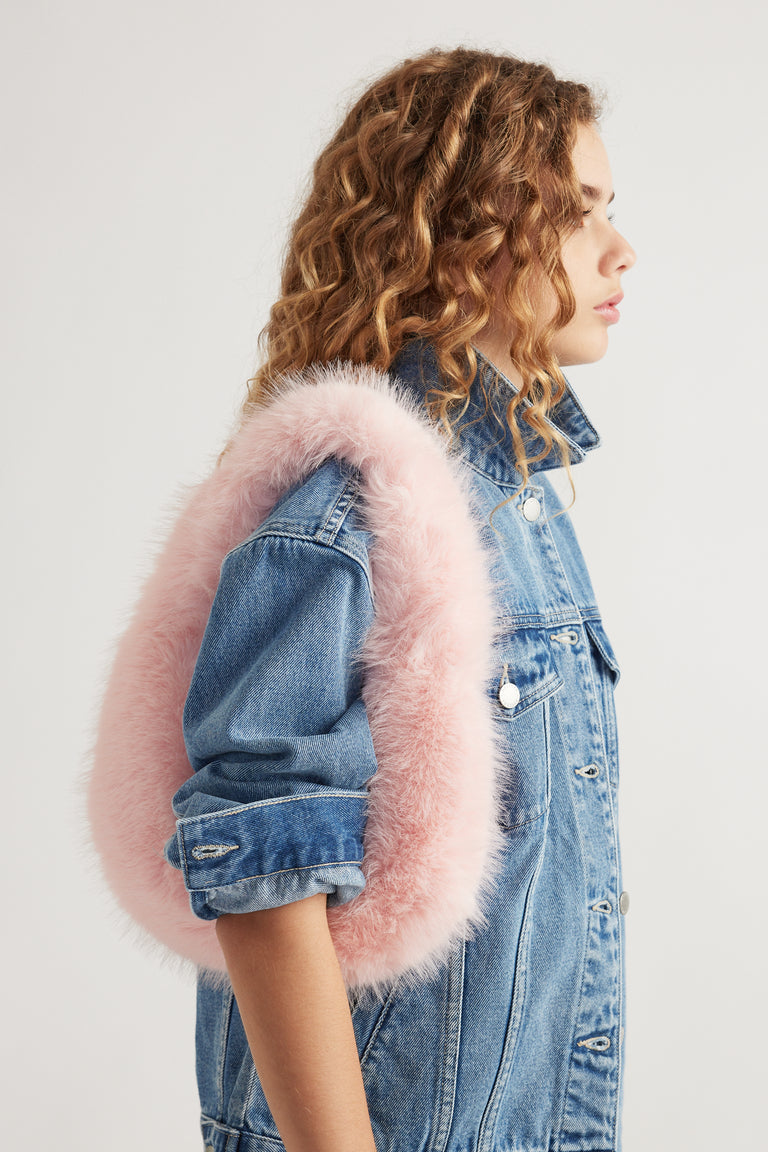 Side view of girl wearing a pink fluffy shoulder bag with a light wash denim jacket