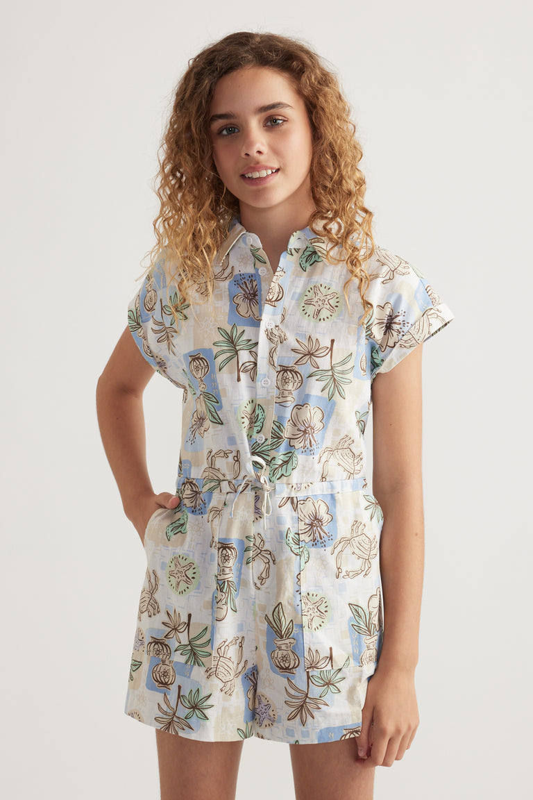 Girl wearing a floral print short sleeve playsuit with a collar, button front and adjustable waist tie