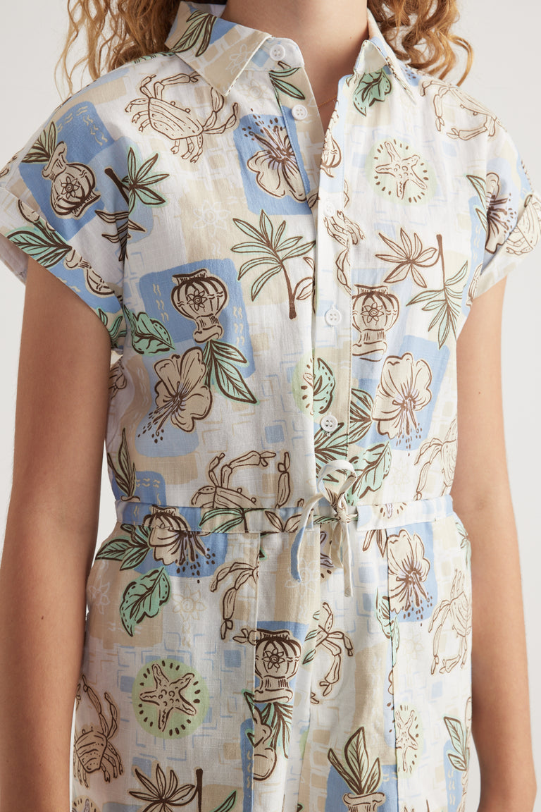 Girl wearing a floral print playsuit with short sleeves, collared neckline, button front and waist tie