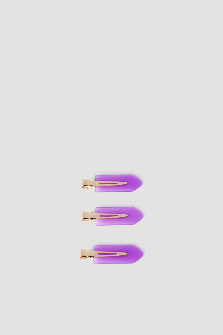 Set of three purple arrow-shaped hair clips with gold-toned metal clasps displayed on light background.