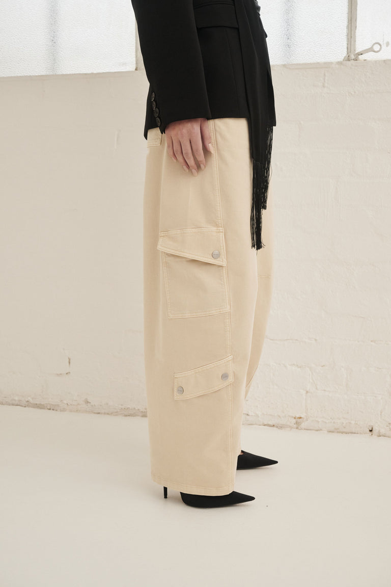 Model wearing cream barrel cargo pants with utility patch pockets and a full length fit