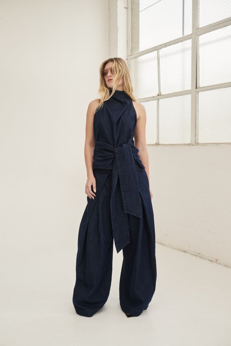 Woman wearing a navy sleeveless funnel neck top with waist tie and matching wide leg pants