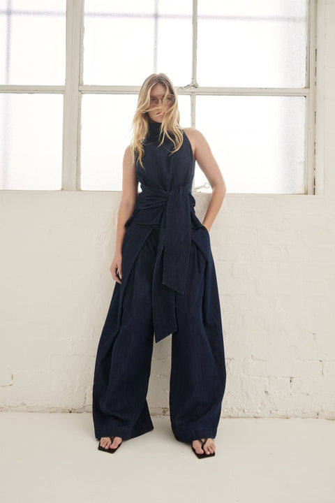 Woman wearing dark navy wide leg denim pants with a draped sleeveless top and black sandals