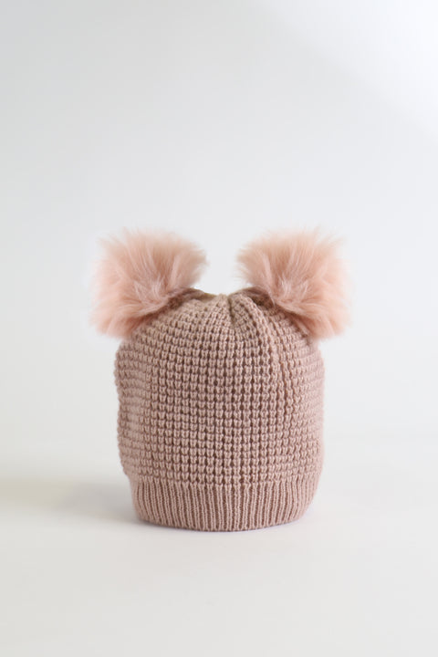 Soft pink knitted girls beanie with two fluffy pom pom details, cozy and stylish winter accessory